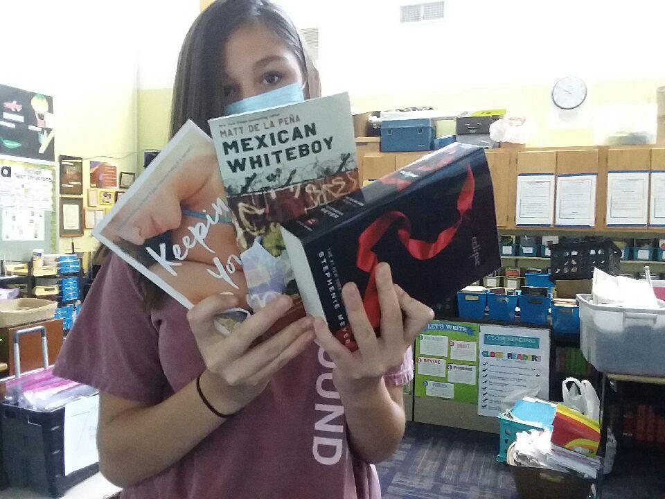 Student in mask choosing books for remote learning